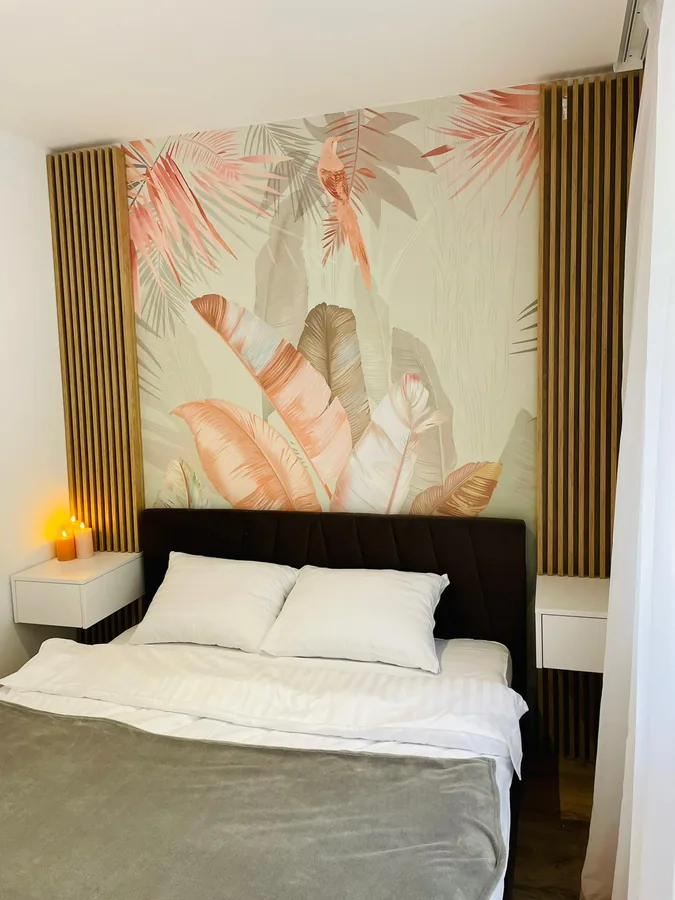 Upholstered headboard with tropical wallpaper and scented candles